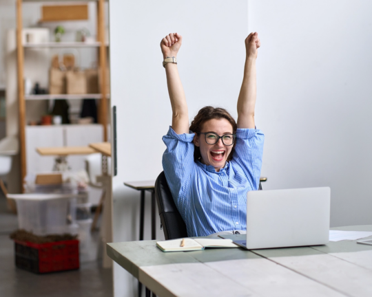 woman happy at desk with arms up